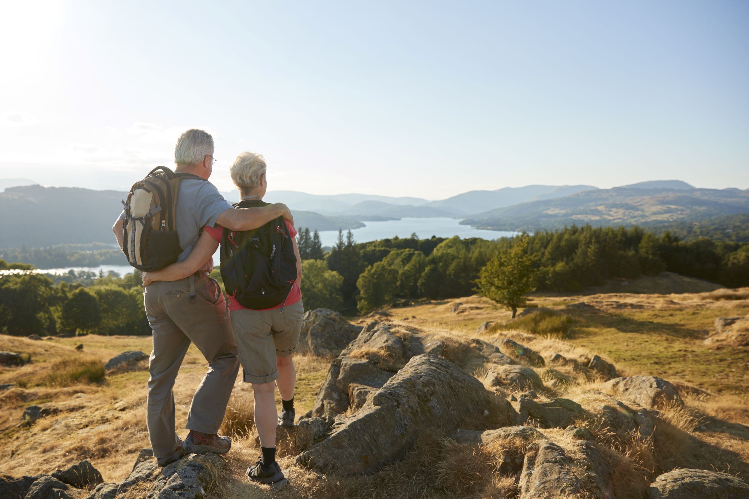 Man and woman looking over the landscape from the top of a large hill.